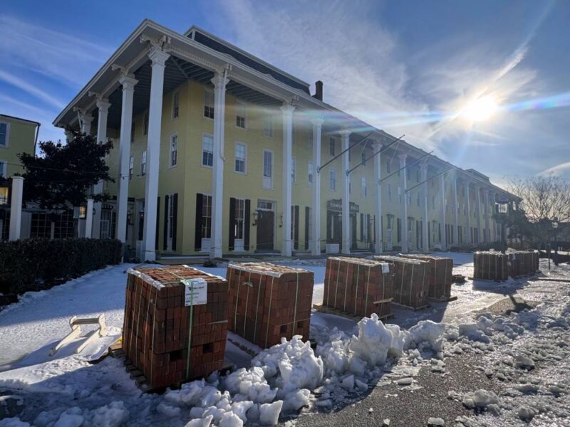 Pallets of brick pavers line the sidewalk amongst snow and ice in front of Congress Hall's Valet 