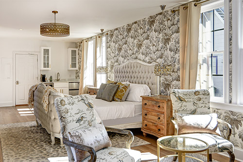 A guest room at the Harrison, upholstered king bed with patterned chairs and wallpaper