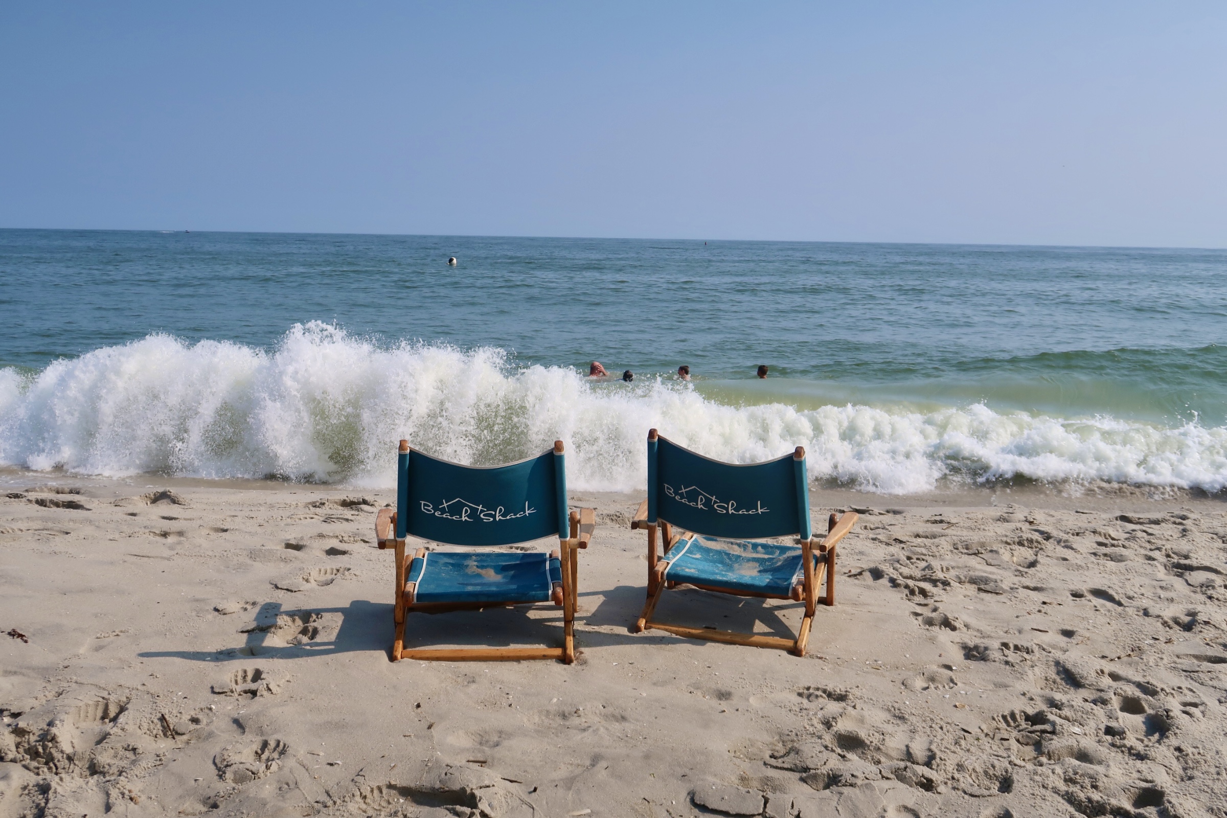 Waves crash on the shore in front of Beach Shack chairs