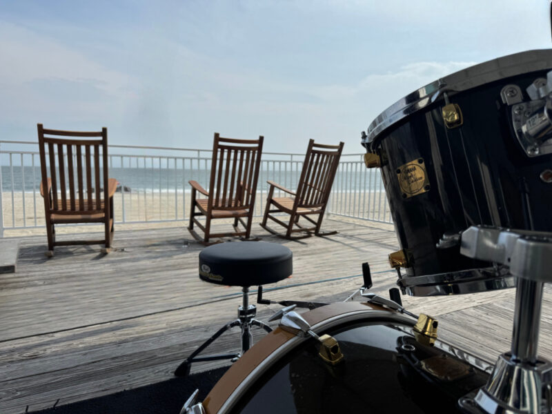 shot of the ocean from behind a drum set and rocking chairs