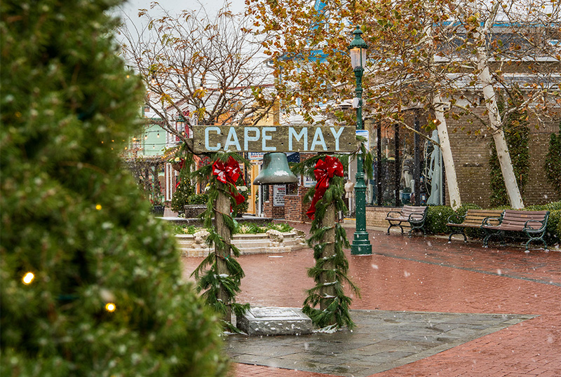 Cape May bell on the Washington Street Mall decorated in greenery and red ribbons. Snow is falling